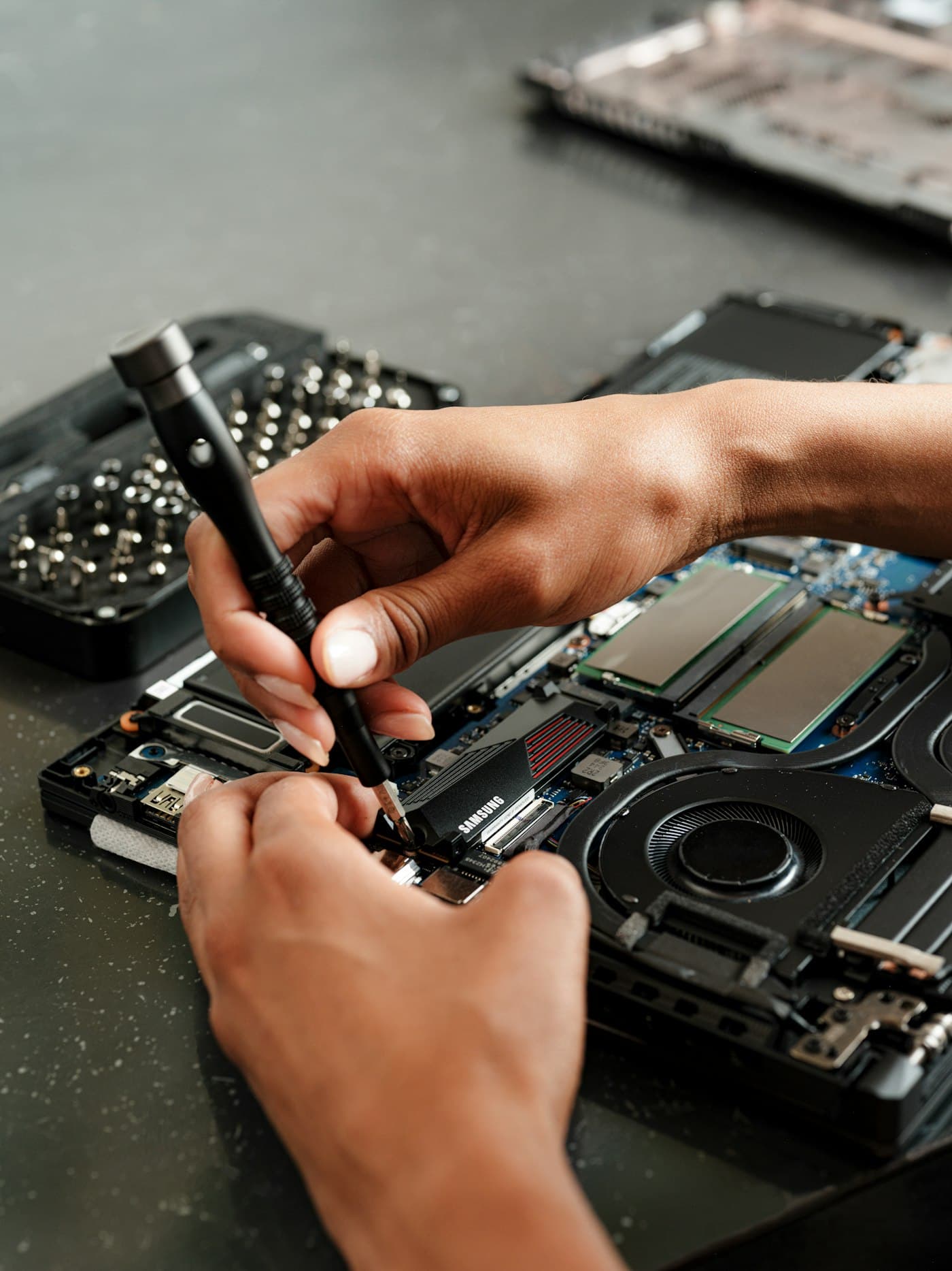 Close work at the repair bench — steady hands on a circuit board under good light