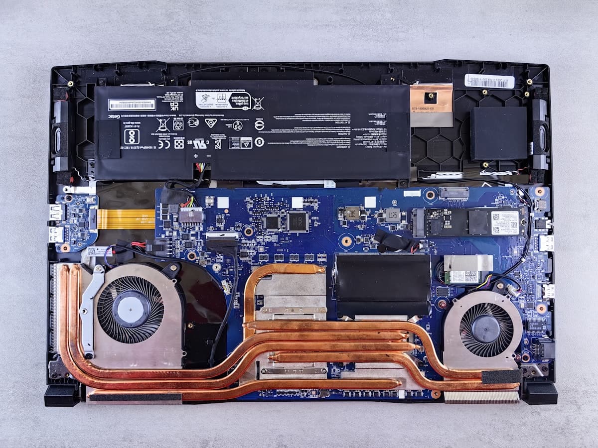 A laptop opened for repair, cooling fans and board exposed